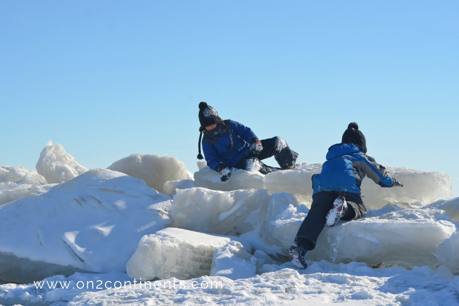 Children climbing ice hills on a day trip to Lake Erie on a sunny winter day.